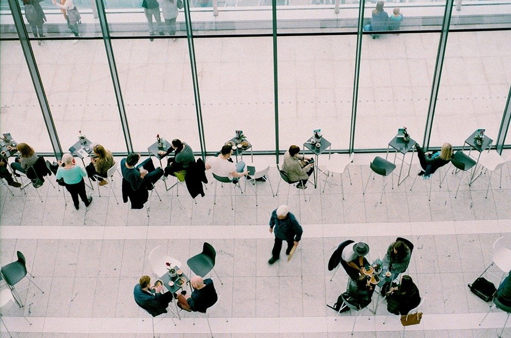 on a une vue de haut sur un hall, il y a pleins de personnes avec des ordinateurs qui travail seule ou par groupa allant jusqu'à 3