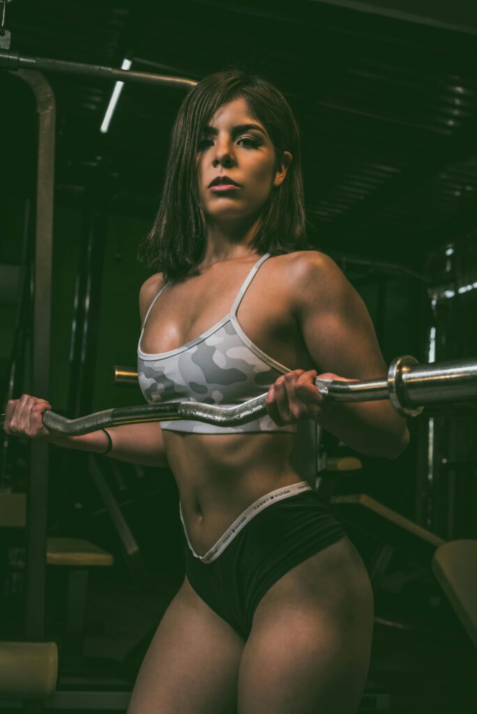 Athletic woman lifting a barbell in a gym, showcasing strength and fitness.