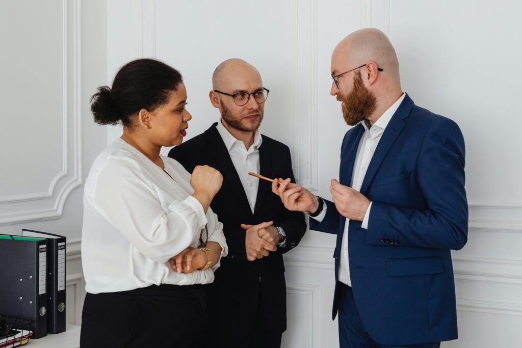 Three professionals engaged in a business discussion in an office setting.