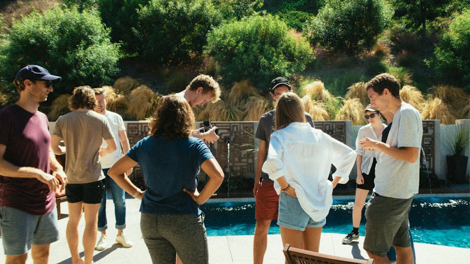 A group of friends enjoys a sunny day by the pool, engaged in conversation.