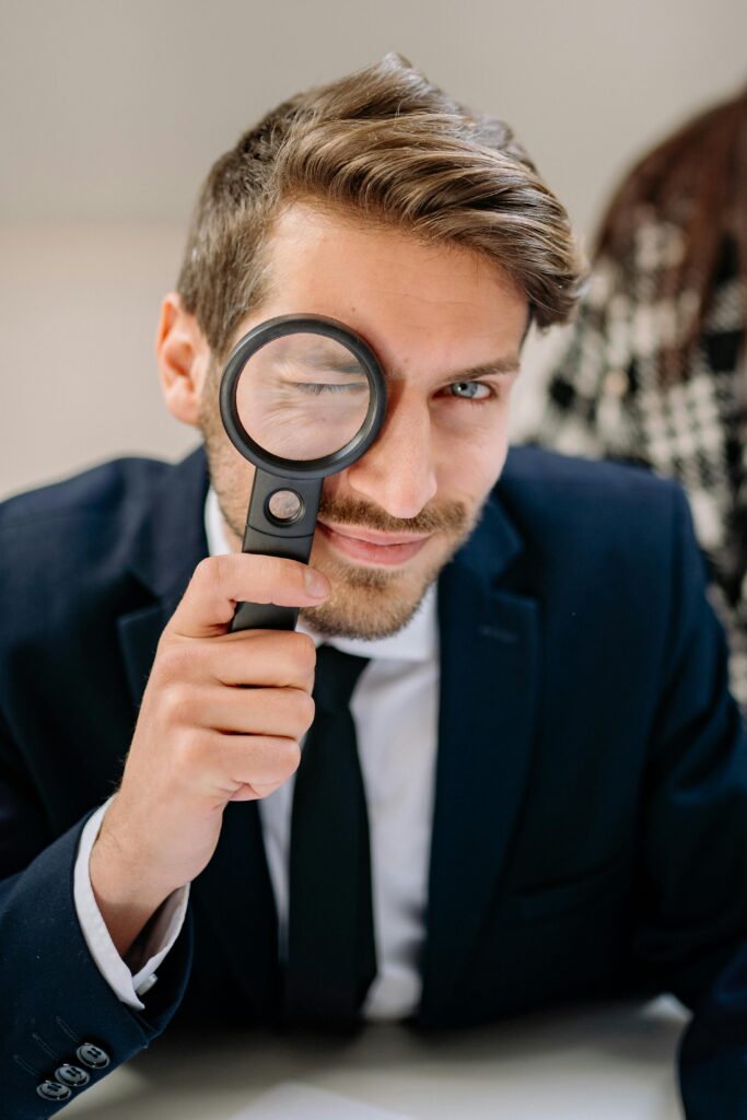 Jeunes homme montrant qui nous somme par le fait d regarder dans une loupe 