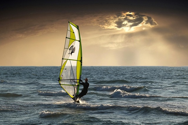 windsurfer sur la mer avec les rayons sur soleil qui sortent des nuages