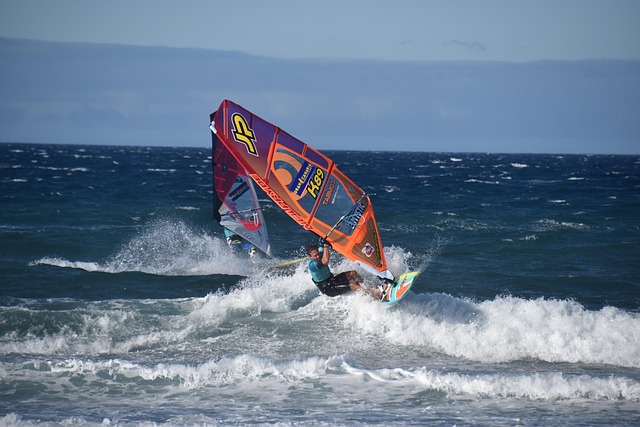 Un windsurfeur participe à une course dans les vagues face à un concurrent qui tente de le dépasser.