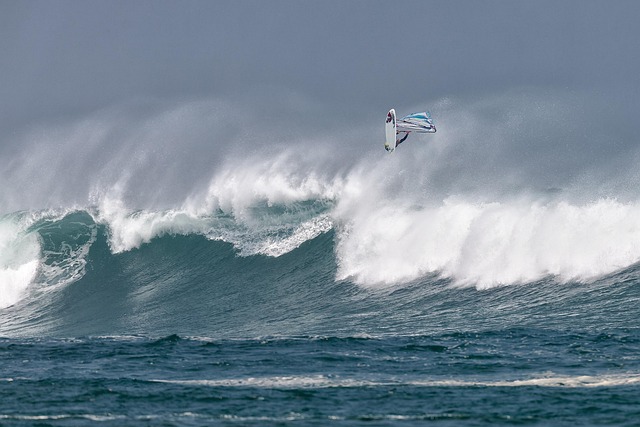 Windsurfer entrain de volet au dessus d'une géante vague