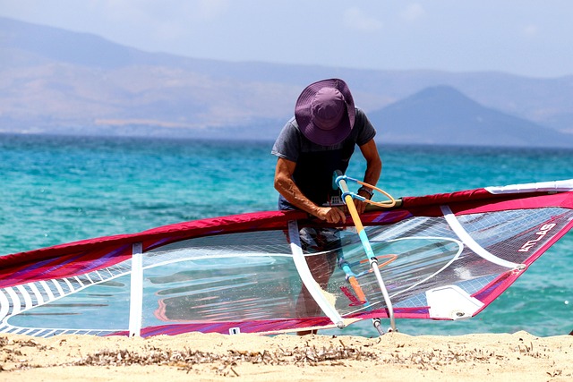 Windsurfer entrain de préparer sa planche avec une eau turquoise en arrière plan